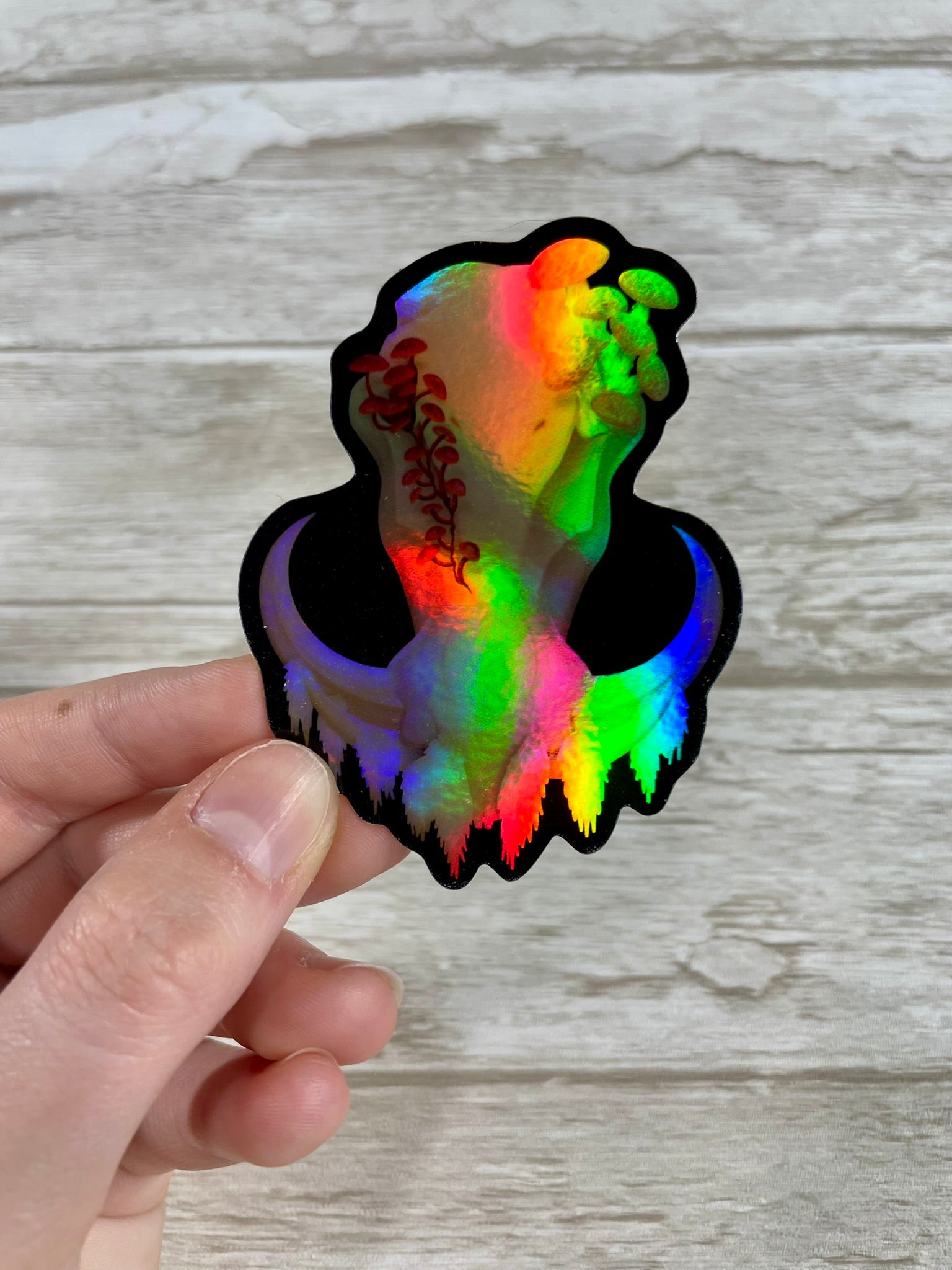 A holographic, die cut, 3 inch tall, vinyl sticker featuring a front facing warthog skull with 3 different kinds of fungi growing out of it