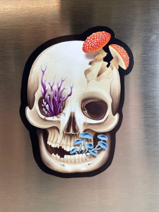 A magnet on a fridge that features a human skull with various fungi growing out of it 