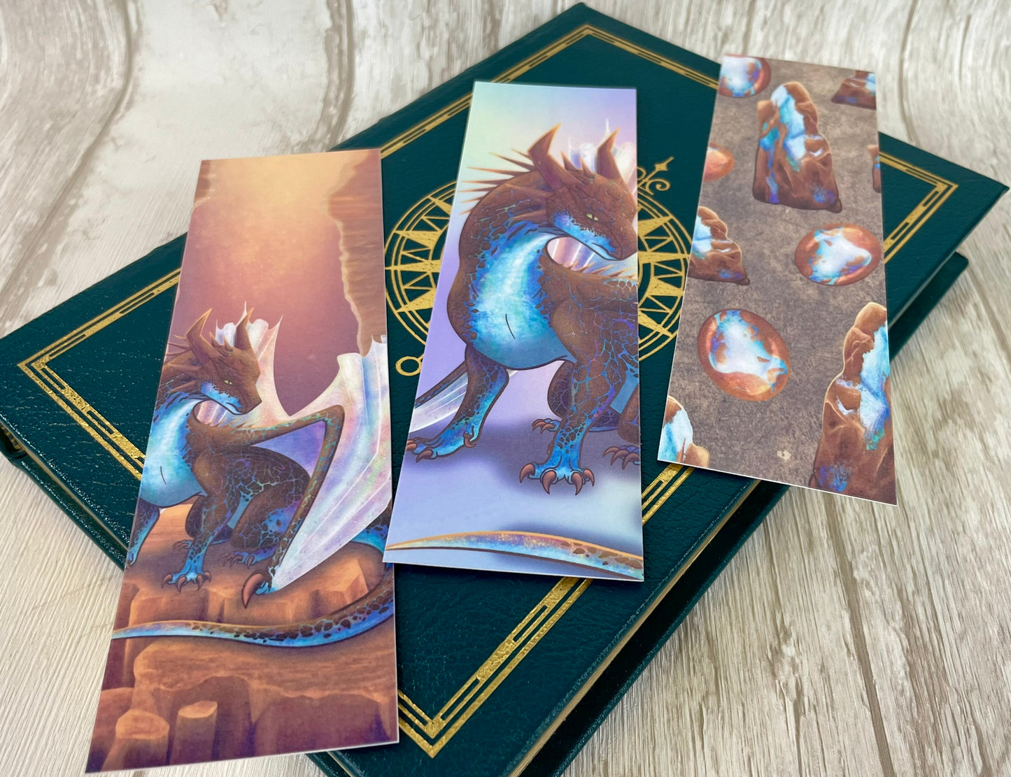 All 3 Opal Mineral Dragon bookmarks all measuring 2 by 7 inches laying across on a book