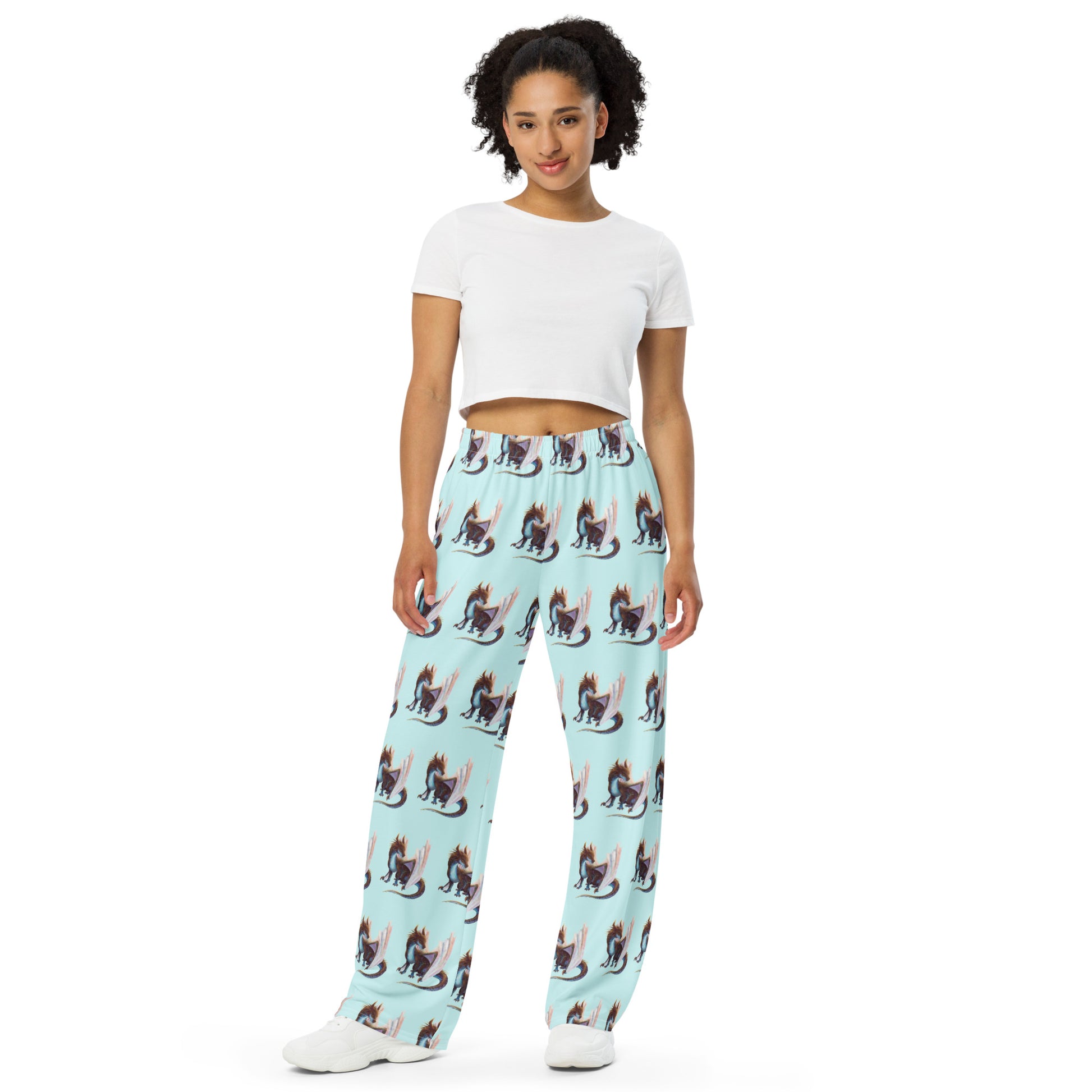 Front view of unisex, light bluish green in color all over print pajama pants featuring a sitting, side profile of a dragon that has the features of a boulder opal with hues of blue, green, purple, and pink on the underbelly and cracks of the rough, brown hue, rock scales. The wings are tucked back and are of an iridescent shimmery hue