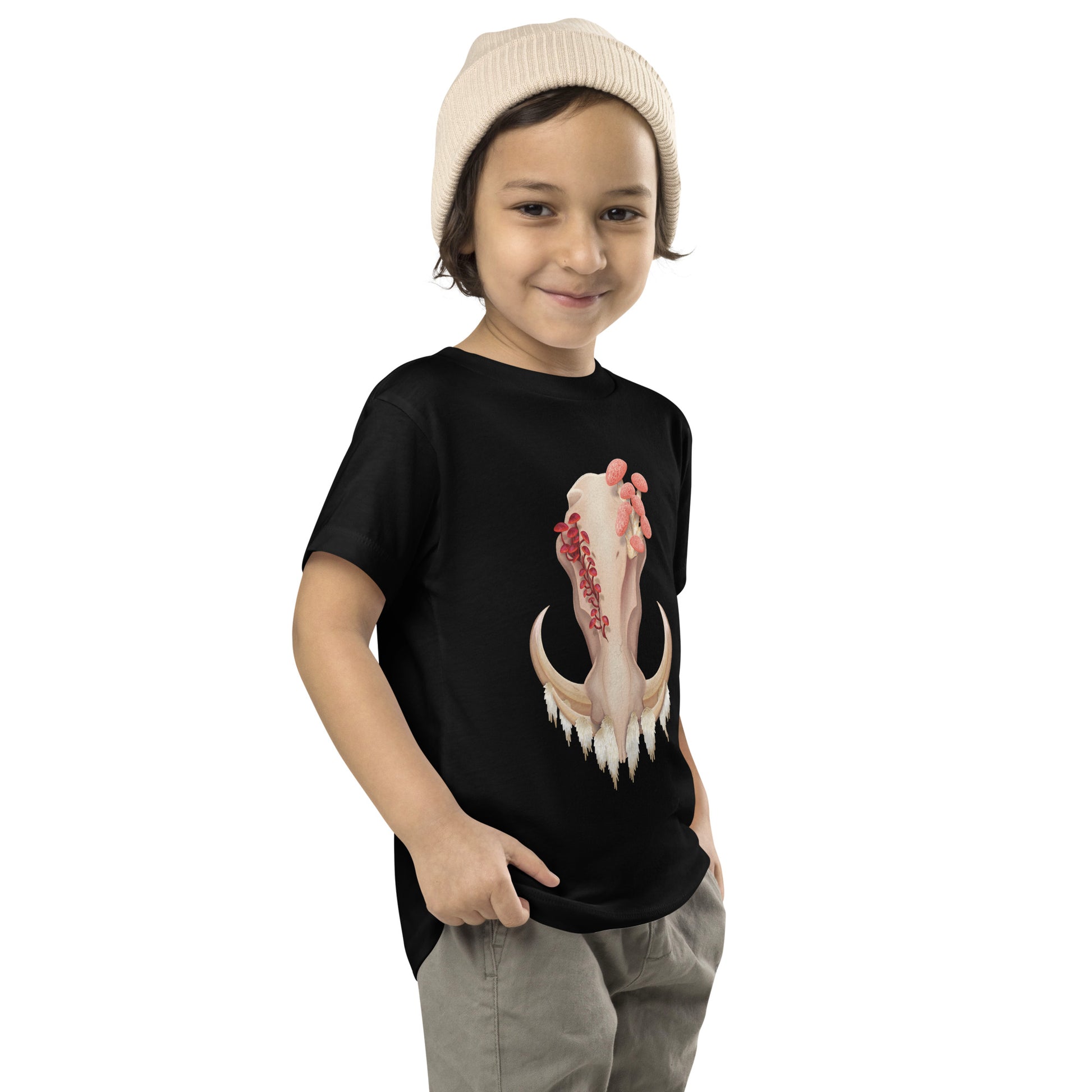 A toddler wearing a black T shirt featuring a front facing warthog skull with 3 different kinds of fungi growing out of it