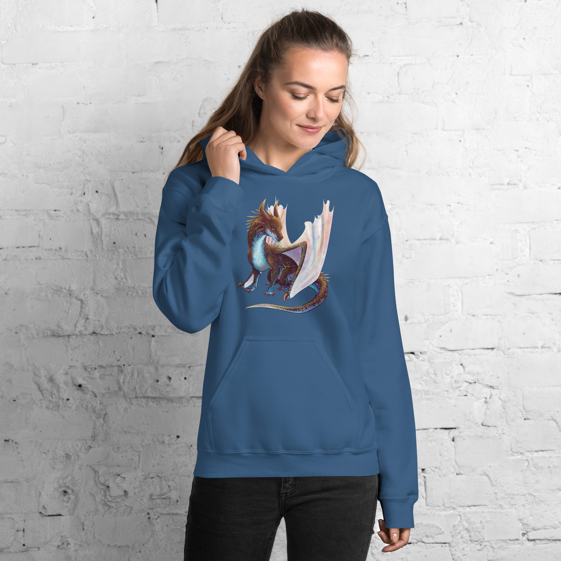 Unisex, indigo blue in color adult hoodie with a pocket in front featuring a sitting, side profile of a dragon that has the features of a boulder opal with hues of blue, green, purple, and pink on the underbelly and cracks of the rough, brown hue, rock scales. The wings are tucked back and are of an iridescent shimmery hue