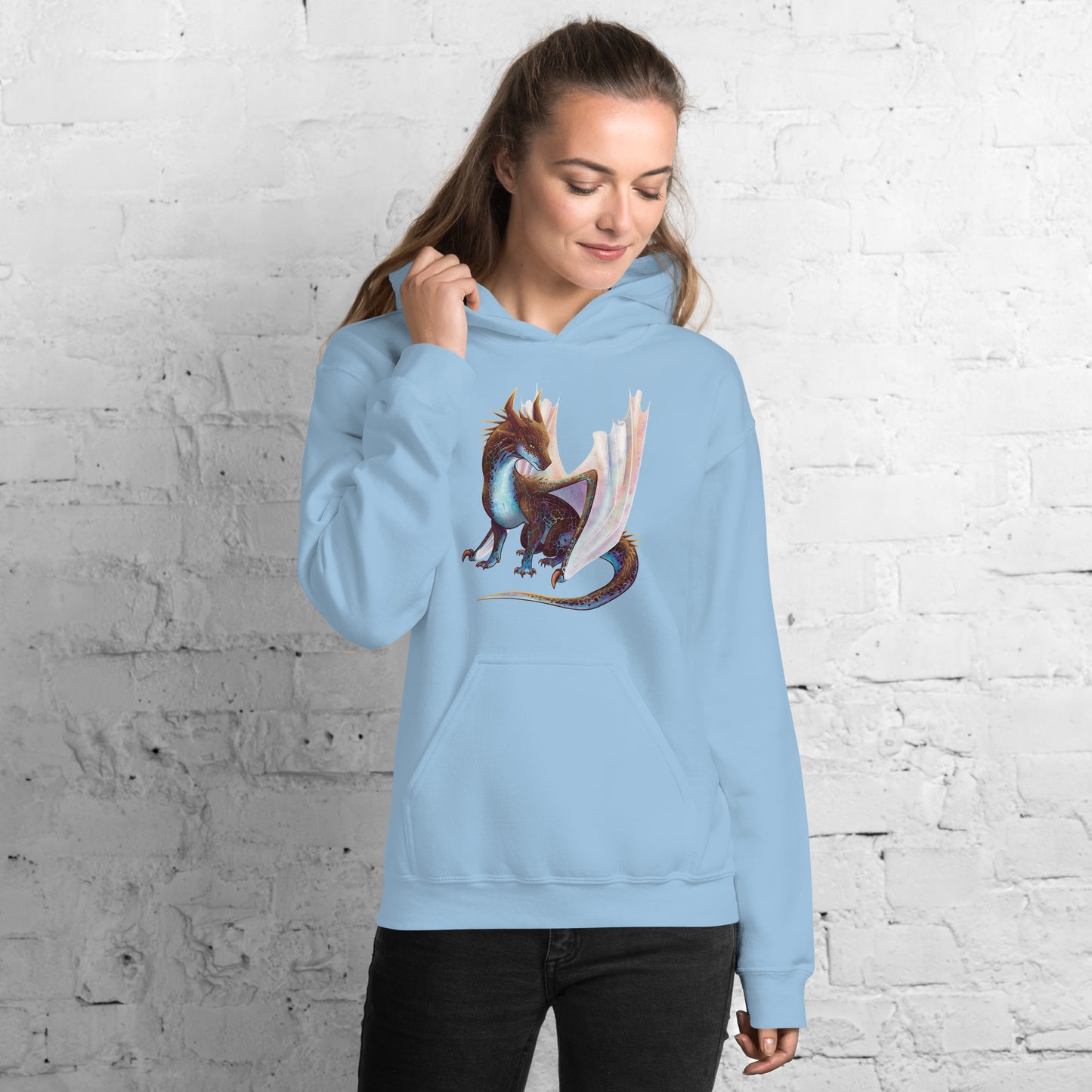 Unisex, light blue in color adult hoodie with a pocket in front featuring a sitting, side profile of a dragon that has the features of a boulder opal with hues of blue, green, purple, and pink on the underbelly and cracks of the rough, brown hue, rock scales. The wings are tucked back and are of an iridescent shimmery hue