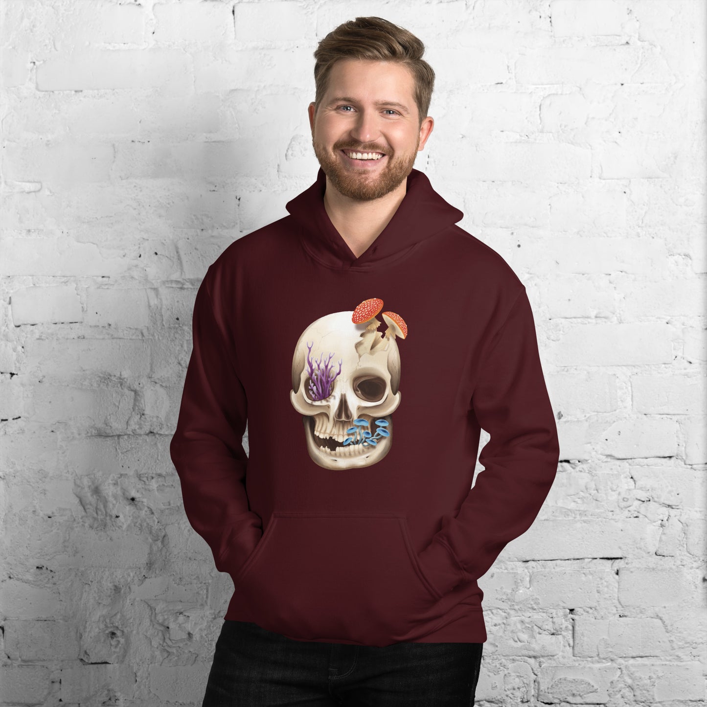 A maroon adult hoodie with a front hand pocket featuring a front facing human skull with 3 different kinds of fungi growing out of it