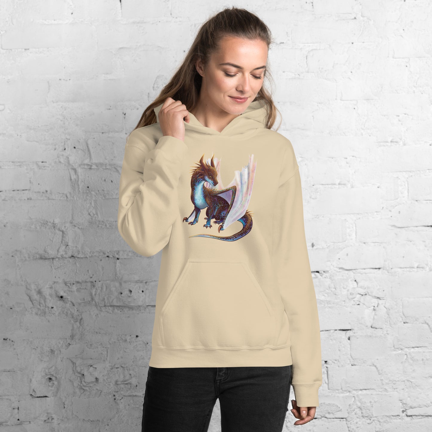 Unisex, sand in color adult hoodie with a pocket in front featuring a sitting, side profile of a dragon that has the features of a boulder opal with hues of blue, green, purple, and pink on the underbelly and cracks of the rough, brown hue, rock scales. The wings are tucked back and are of an iridescent shimmery hue