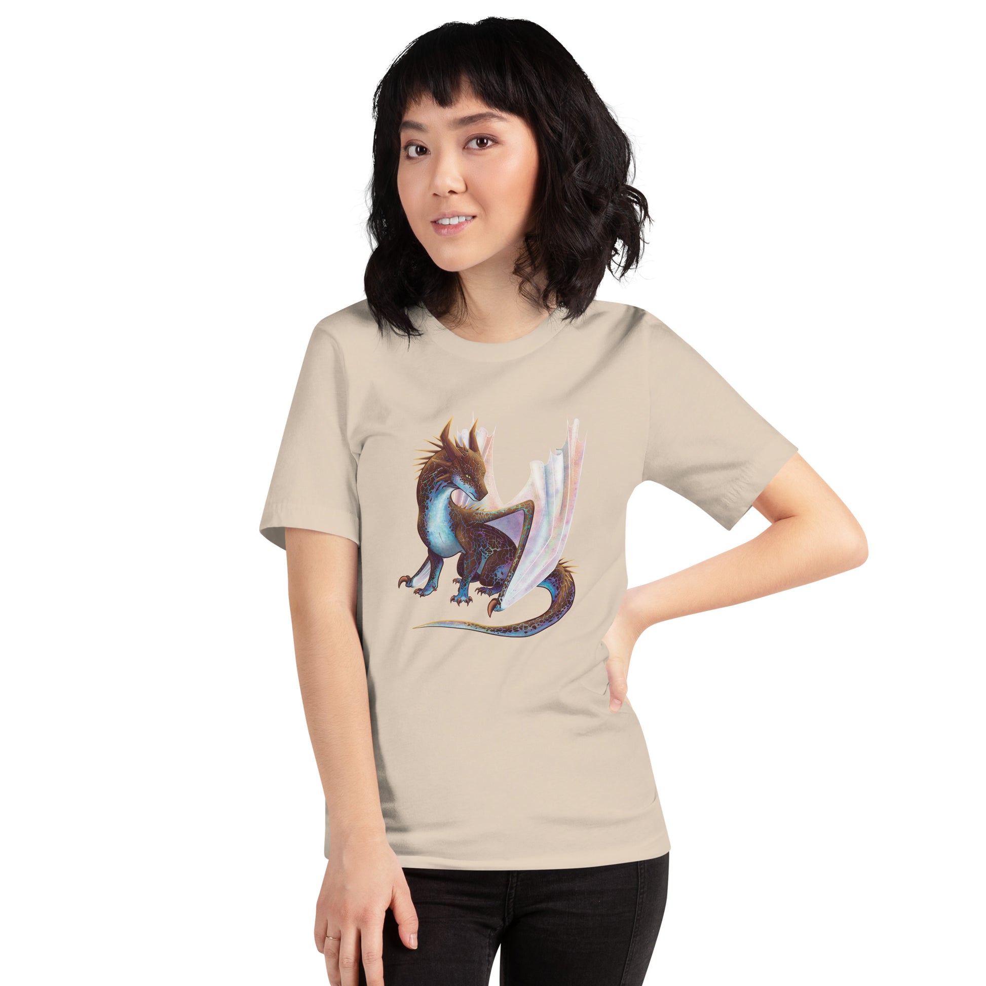 Unisex, soft cream in color adult short sleeve tee shirt featuring a sitting, side profile of a dragon that has the features of a boulder opal with hues of blue, green, purple, and pink on the underbelly and cracks of the rough, brown hue, rock scales. The wings are tucked back and are of an iridescent shimmery hue